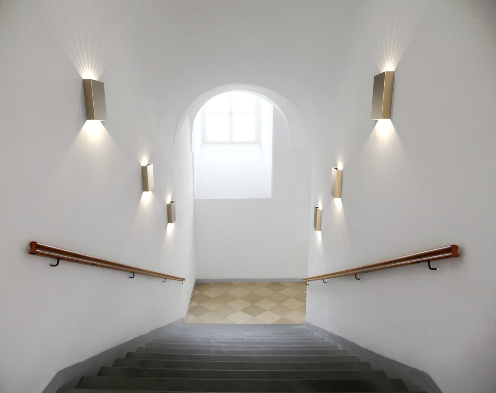 Trappenhuis met wandlampen die licht omhoog en omlaag geven